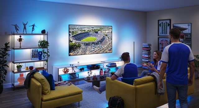 Suasana nobar pertandingan sepak bola di ruang keluarga menggunakan Philips Smart Lighting Connected by WiZ yang menyinkronkan efek cahaya biru di sekitar TV untuk menciptakan pengalaman menonton yang lebih imersif.
