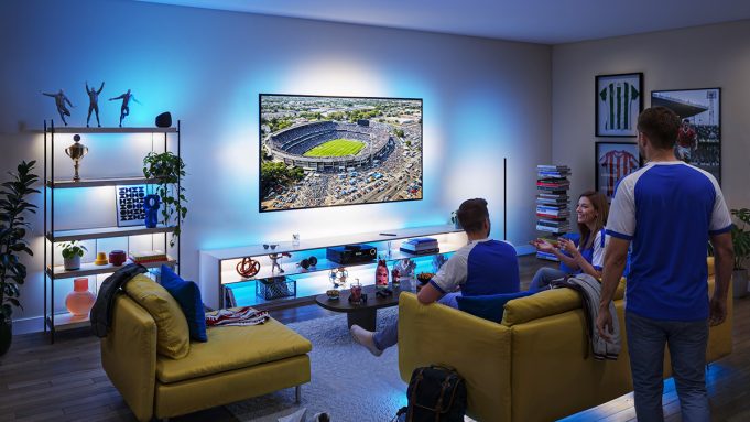 Suasana nobar pertandingan sepak bola di ruang keluarga menggunakan Philips Smart Lighting Connected by WiZ yang menyinkronkan efek cahaya biru di sekitar TV untuk menciptakan pengalaman menonton yang lebih imersif.