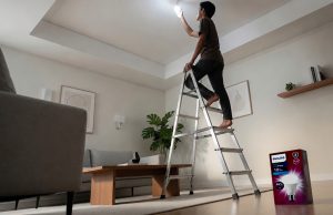 Seorang pemuda memasang bohlam Philips Ultra Bright di plafon rumah
