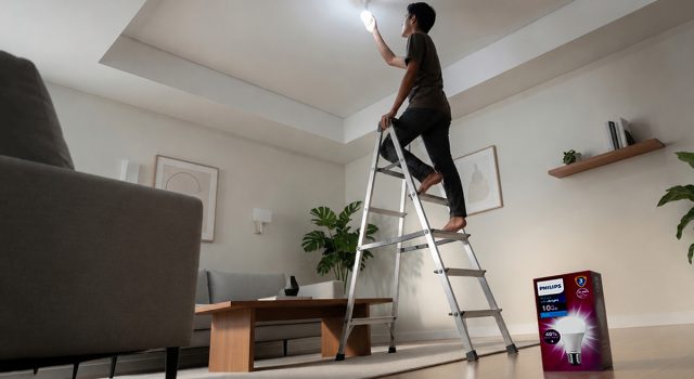 Ketika Rumah Jadi Pusat Kehidupan, Pencahayaan Jadi Penentu Kualitasnya Seorang pemuda memasang bohlam Philips Ultra Bright di plafon rumah