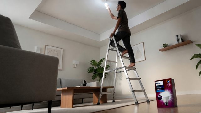 Seorang pemuda memasang bohlam Philips Ultra Bright di plafon rumah