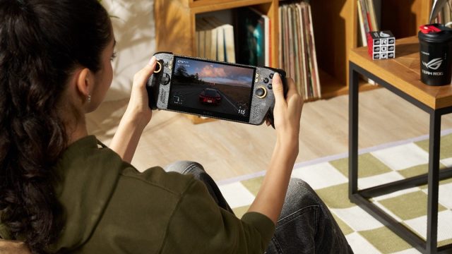 Seorang gamer memainkan ROG XBOX Ally X20, handheld gaming PC edisi 20 tahun ROG, sambil menikmati game balap dengan desain perangkat hitam beraksen emas.