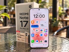 Redmi Note 17 Pro Max 5G dan kotak kemasannya di atas meja kaca bundar bertekstur di kafe dengan pencahayaan alami pagi hari, nuansa warna Fuji yang hangat, serta latar belakang kafe dengan efek bokeh.