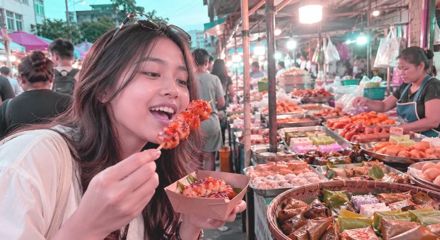 Ilustrasi tren snackpacking di Indonesia, menampilkan wisatawan yang menikmati jajanan lokal di pasar kuliner tradisional dengan beragam makanan khas sebagai daya tarik wisata kuliner.