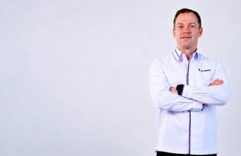 Thomas Hundt Komisaris XLSMART berdiri dengans rsagam xlsmart sambil bersedekap