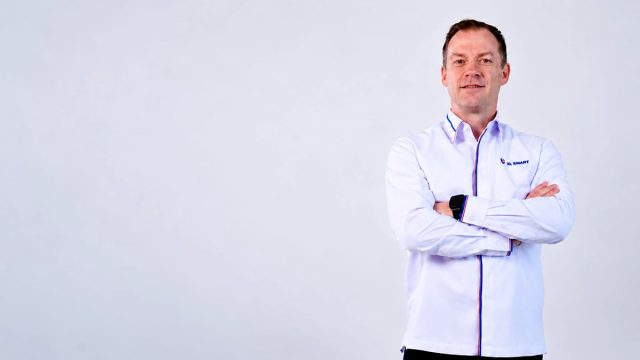 Thomas-Hundt Thomas Hundt Komisaris XLSMART berdiri dengans rsagam xlsmart sambil bersedekap