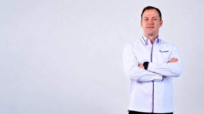 Thomas Hundt Komisaris XLSMART berdiri dengans rsagam xlsmart sambil bersedekap